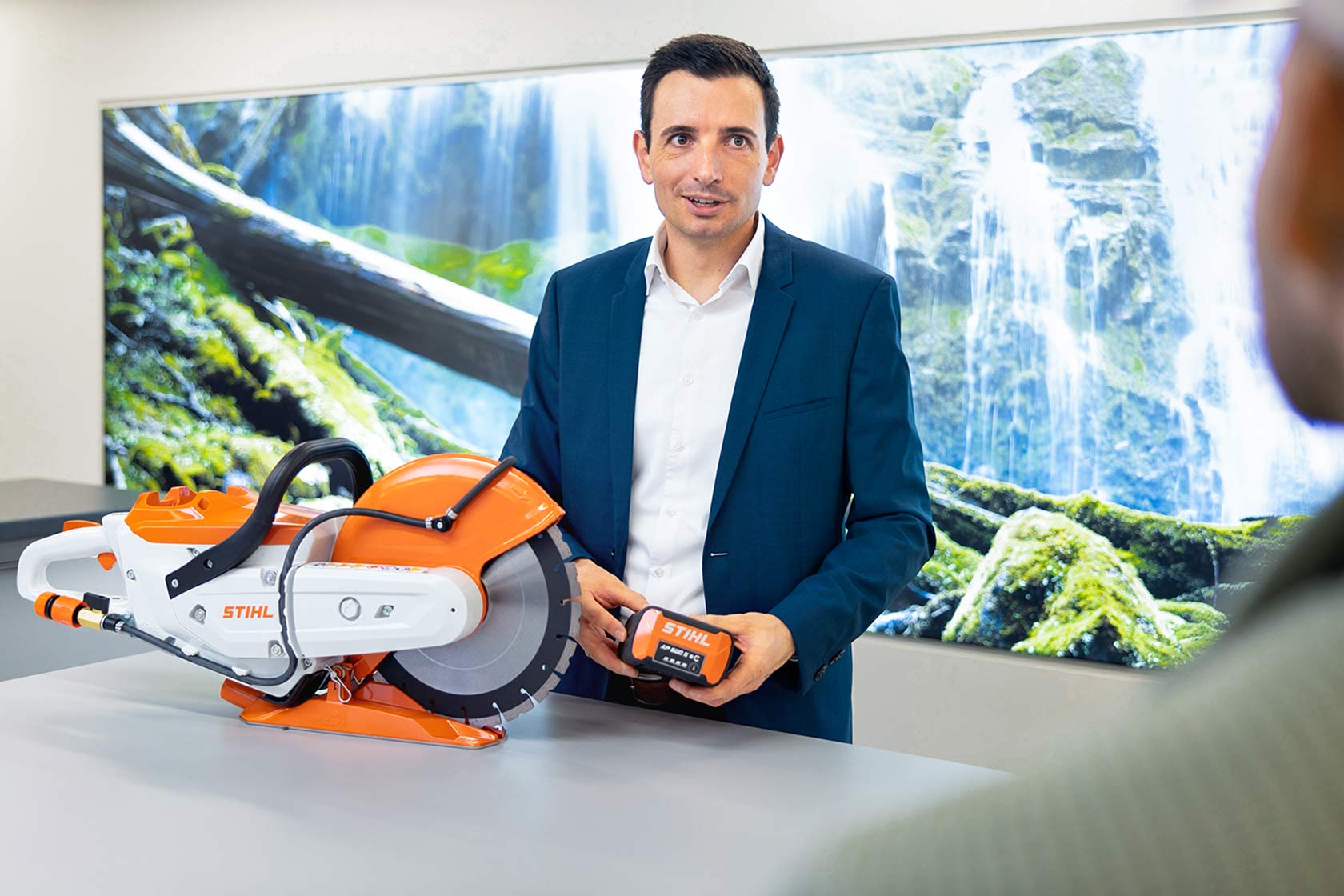 Max Dopatka stands at a table with a cordless cut-off sander in front of him