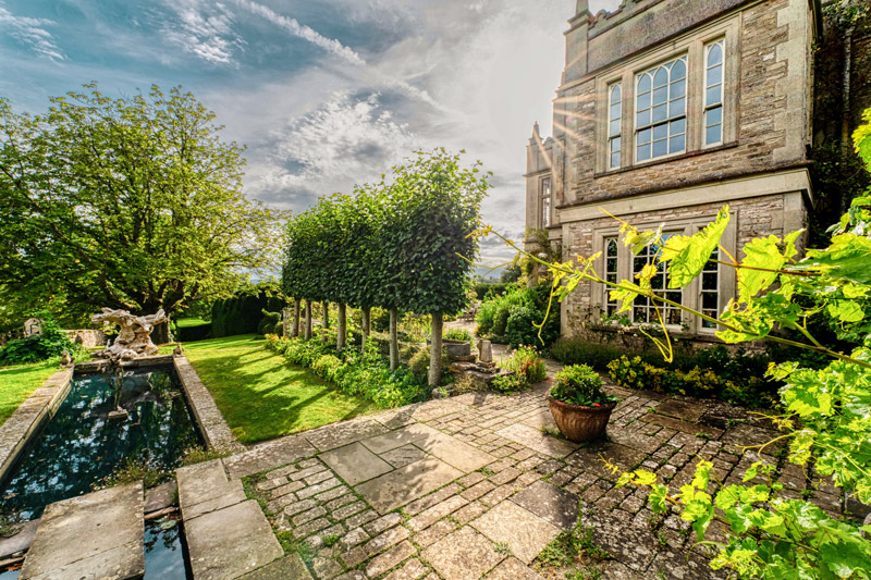 A front of the manor house, in front of it a trellis of lime trees along a square water basin.
