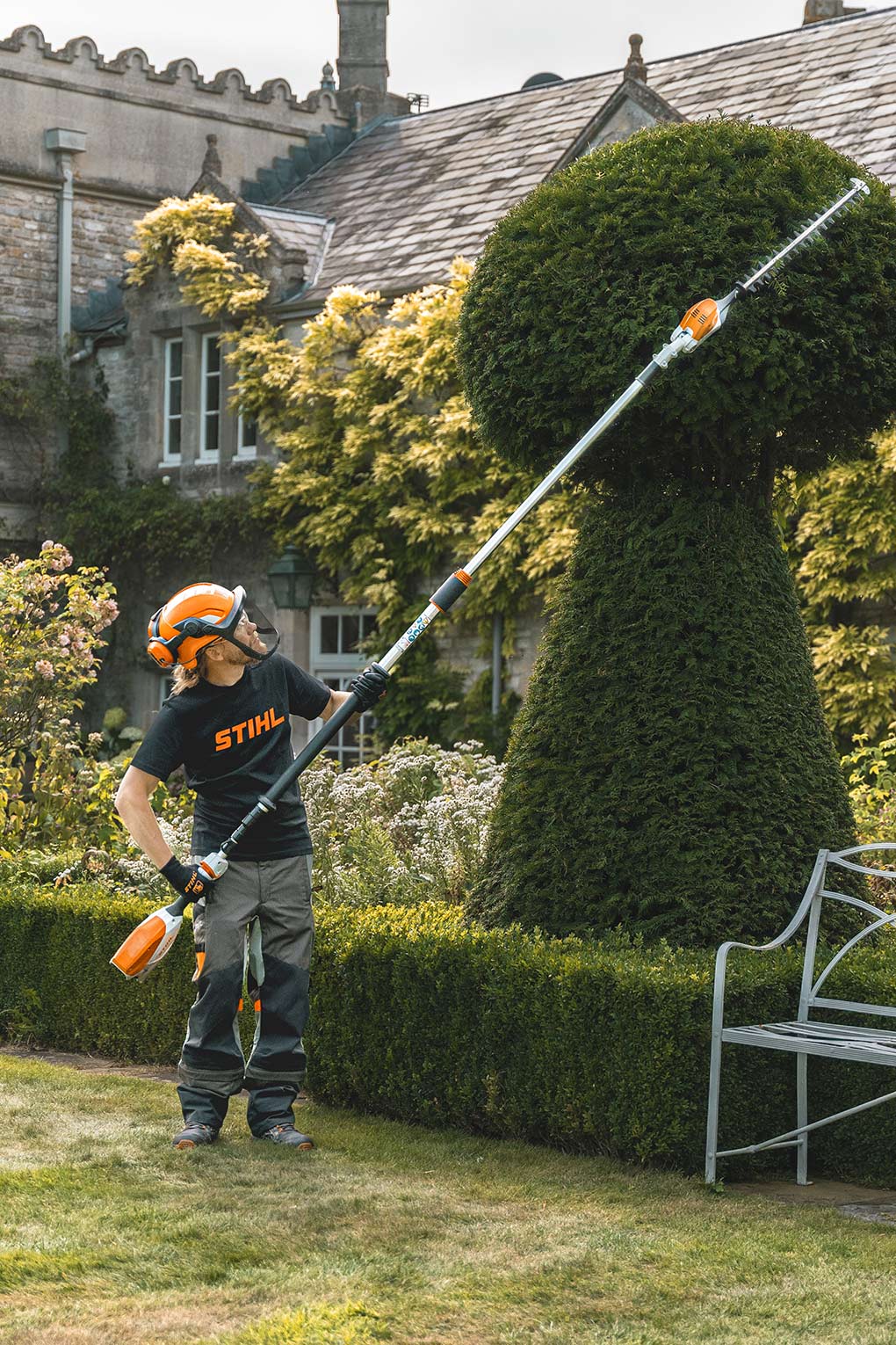Andy Wain uses a telescopic hedge trimmer to cut a yew tree about four metres high into a chess piece.